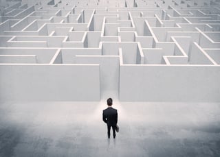 A good looking businessman with briefcase standing in front of white labirynth entrance about to make a decision concept.jpeg