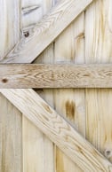 Reinforcing planks in the shape of an arrow across plain wooden fence-1.jpeg